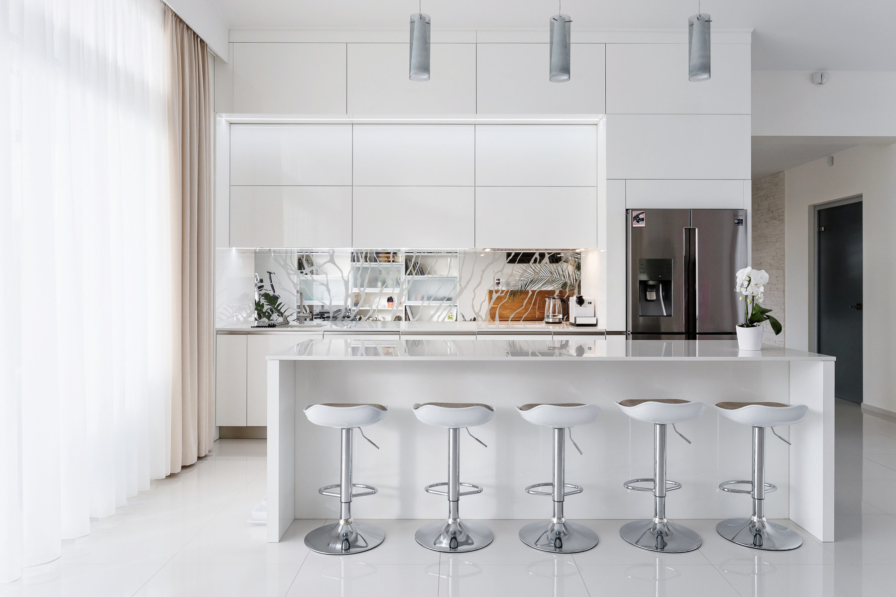 Minimālistiska dizaina virtuves mēbeles baltā krāsā ar virtuves salu.