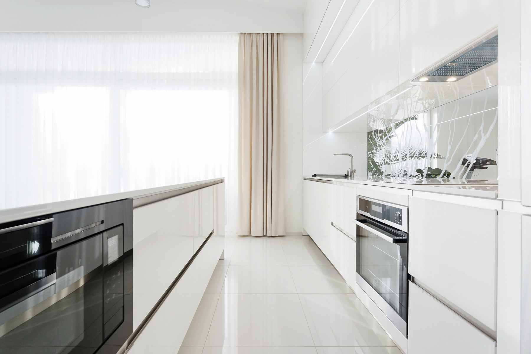 Moderns un gaišs mājoklis ar baltām virtuves iekārtām.