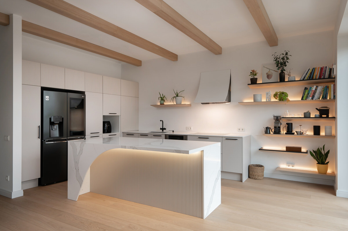 Moderna gaiša virtuve pie divām sienām ar individuāla dizaina salu un koka plauktiem
