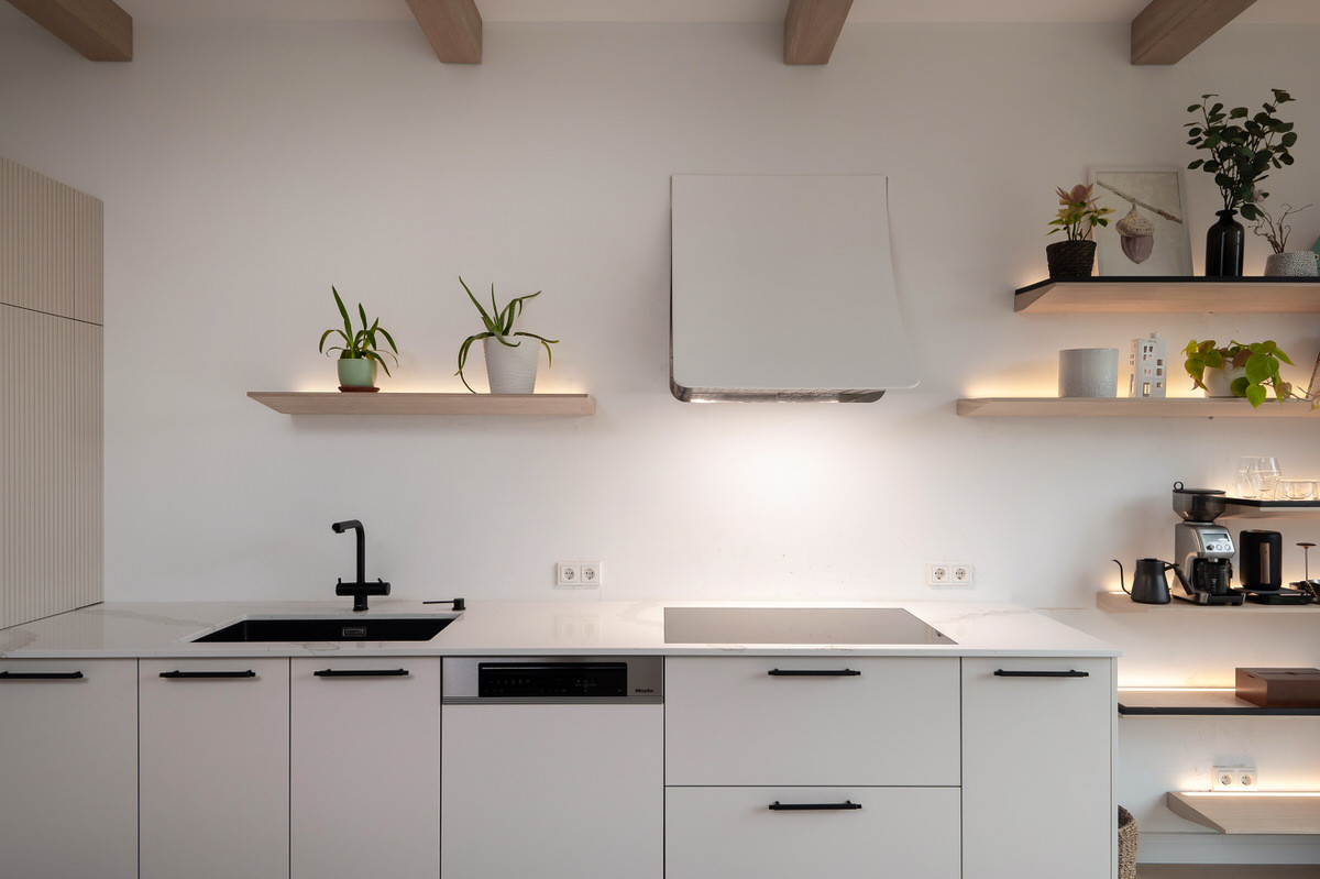 Moderna gaiša virtuve ar īpašu dizaina nosūcēju un individuāliem koka plauktiem